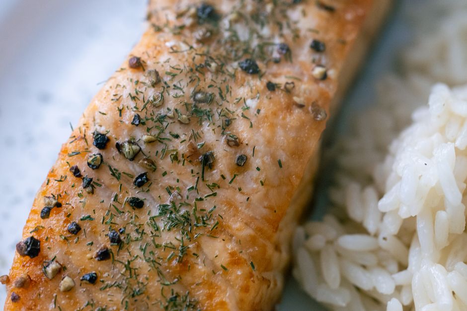 Close-up of a cooked salmon fillet with herbs and rice.