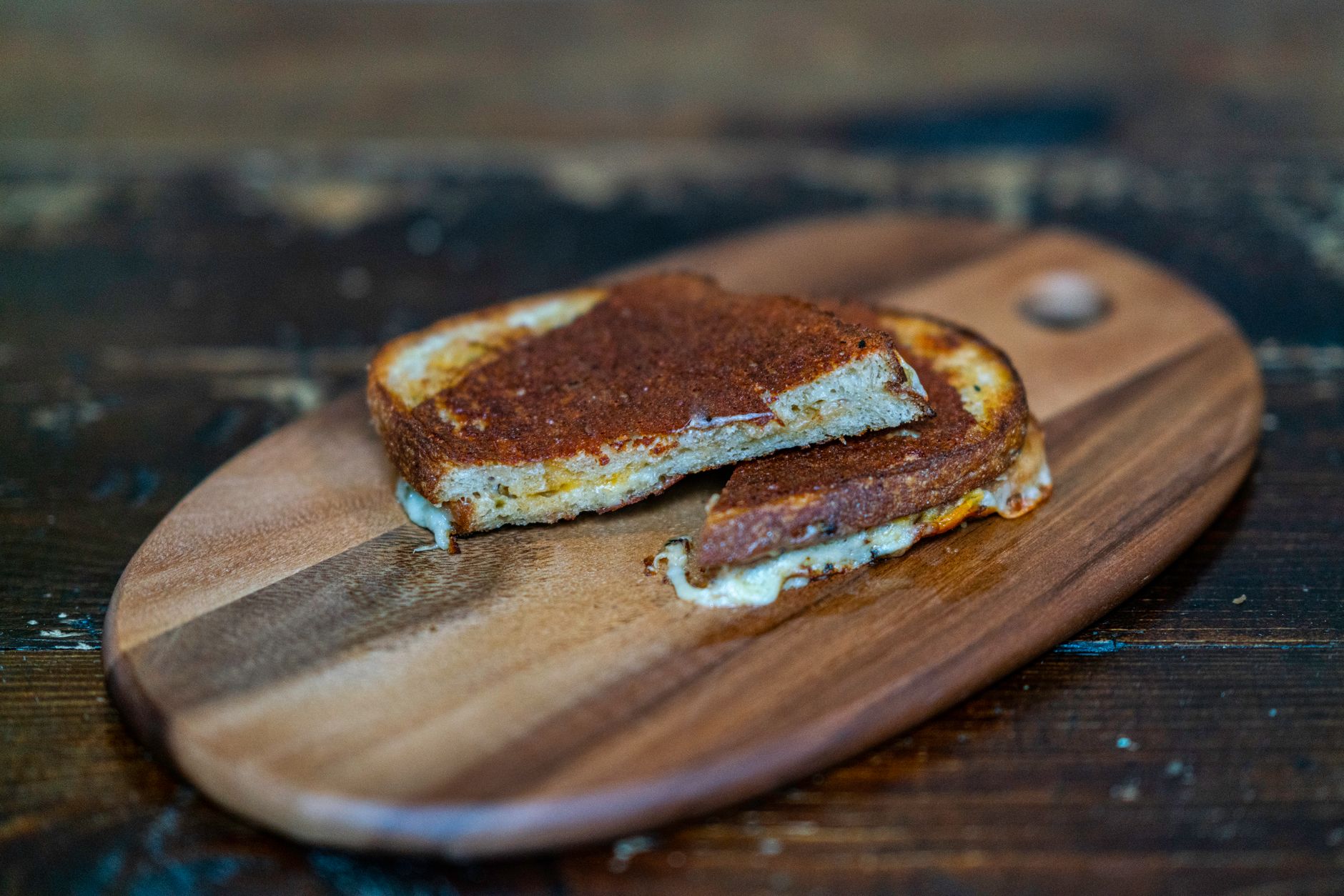 Air fryer grilled cheese for one cut on a wooden board.
