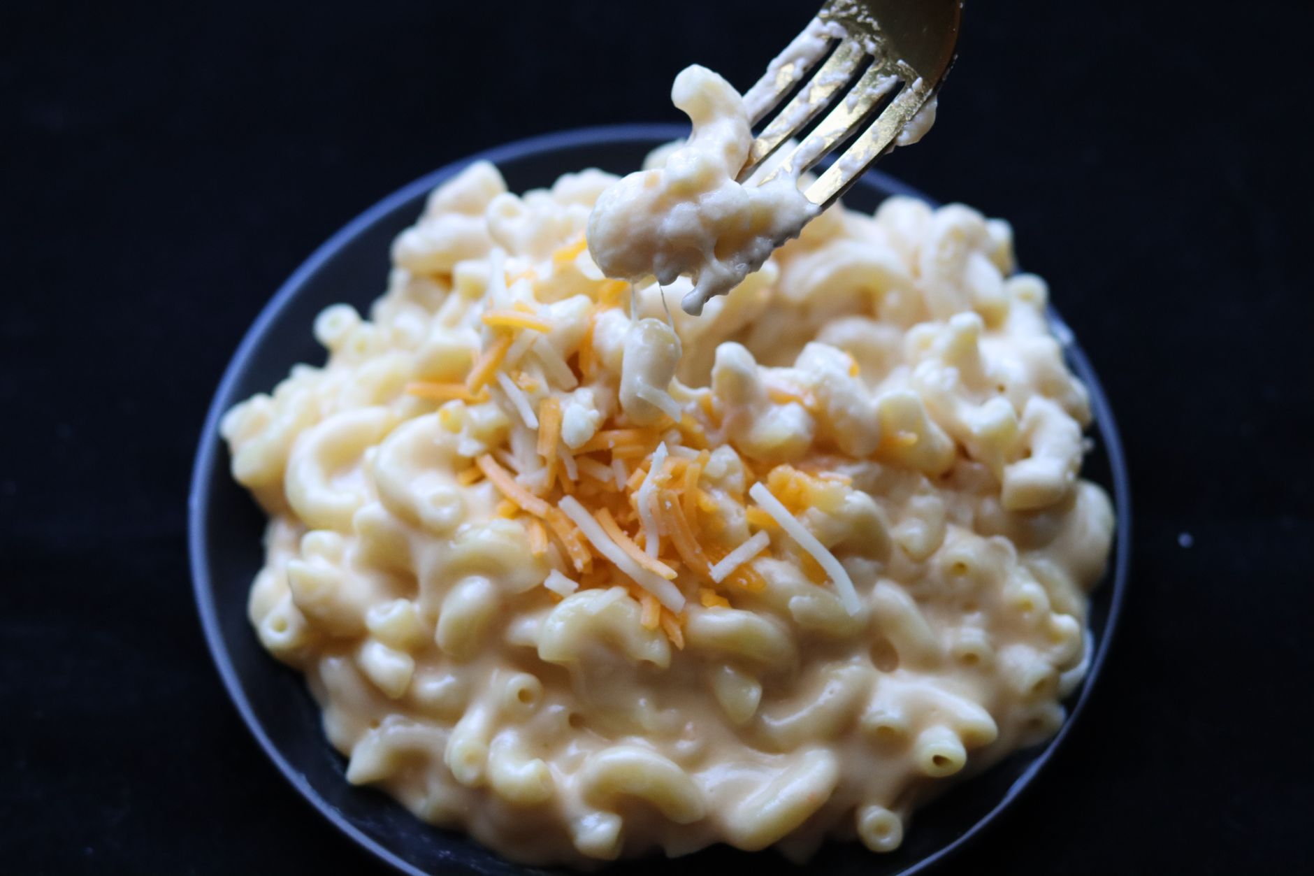 Single serving air fryer mac and cheese in a dark bowl with creamy cheese sauce.