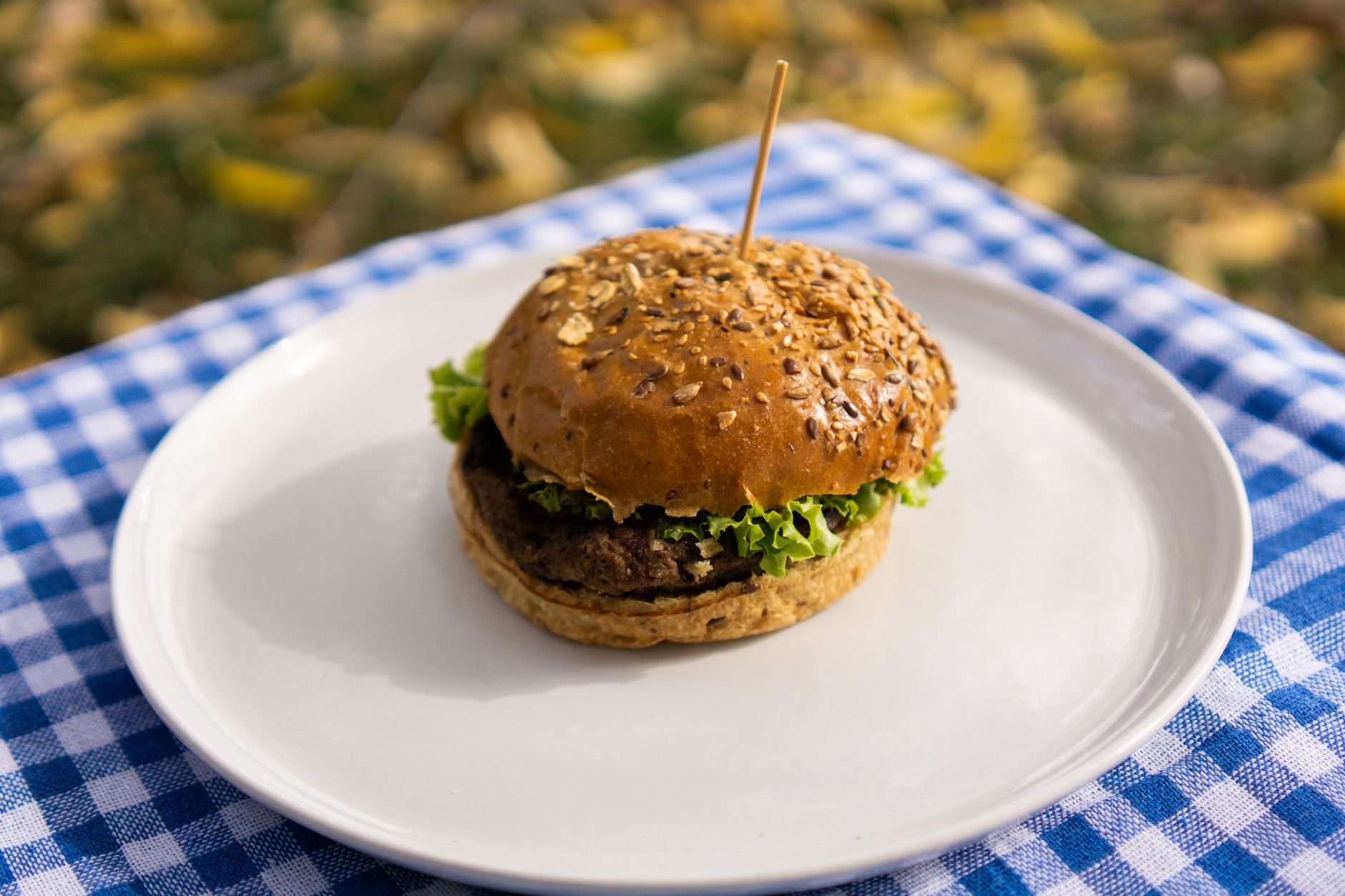 Air fryer beef burger for one serving inspiration: a single burger with lettuce on a white plate.