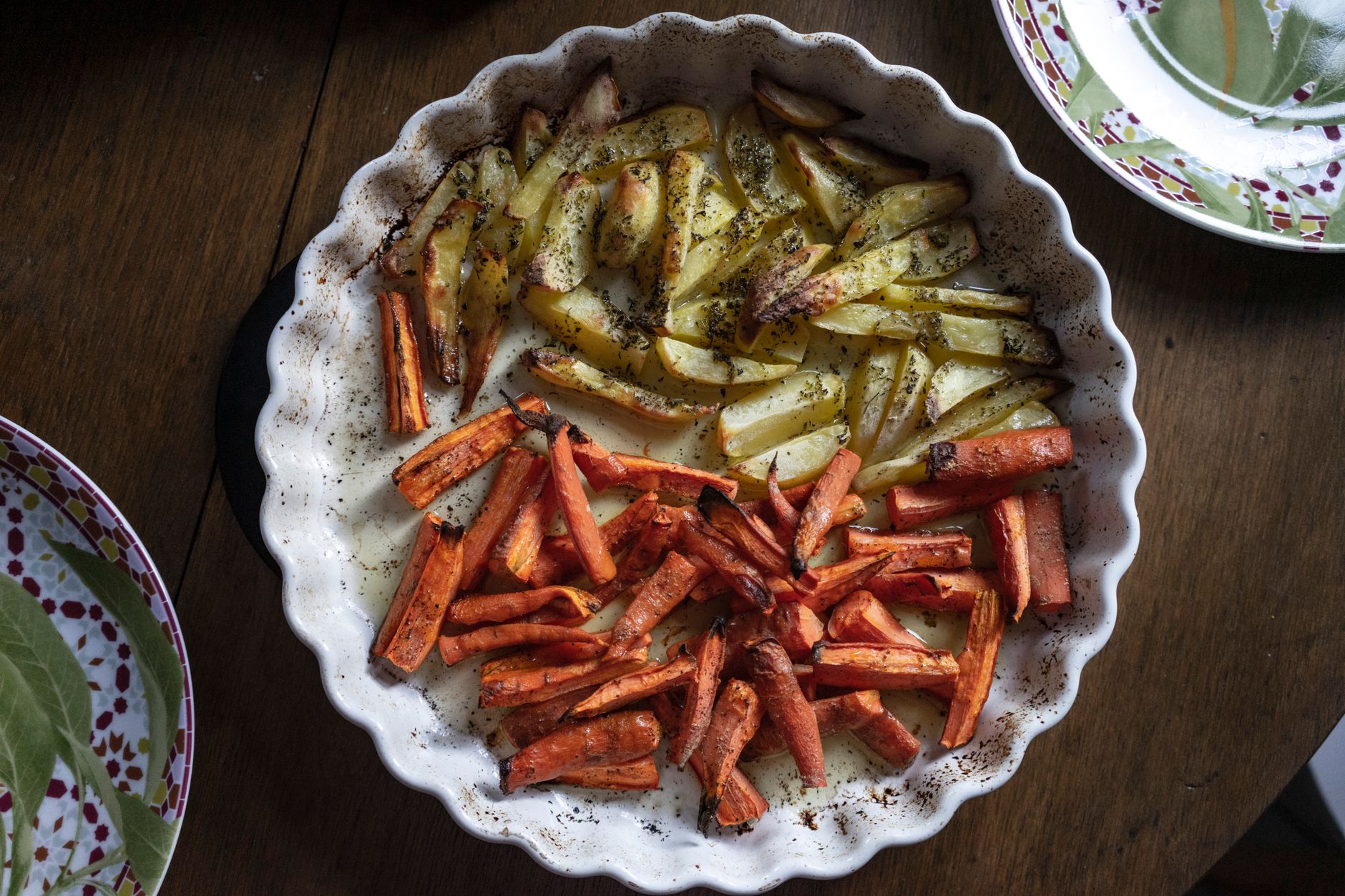 Air fryer carrots for one serving inspiration: roasted carrot batons alongside potatoes in a baking dish.